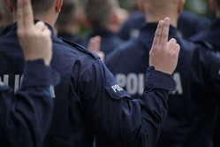 Na zdjęciu uniesione palce nowych policjantów podczas ślubowania.