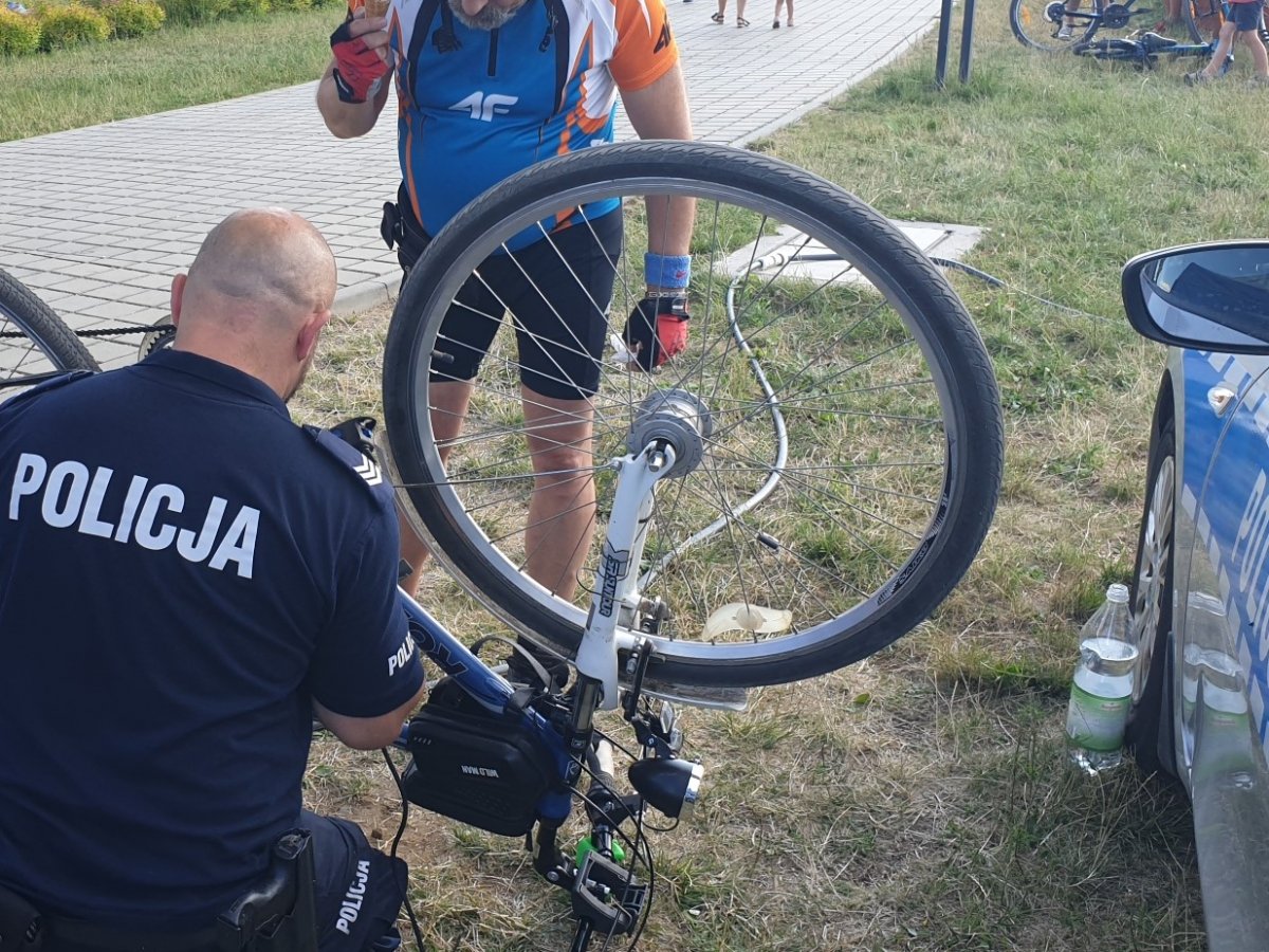 Na zdjęciu widoczny umundurowany policjant, który jest tyłem do obiektywu. Trzyma przed sobą rower i graweruje rowerową ramę.