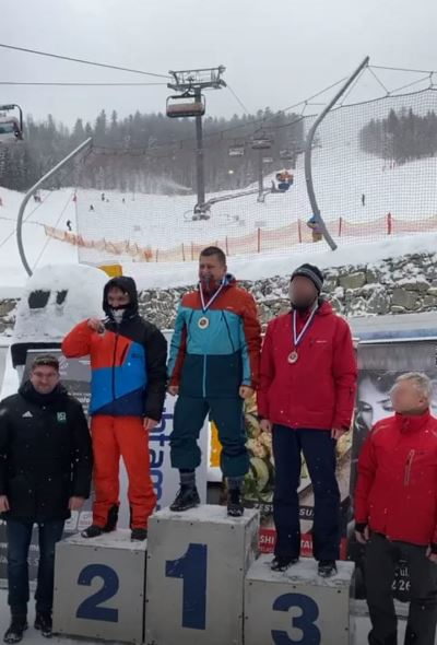 Zawodnicy, którzy zostali wyróżnieni w zawodach narciarskich. Uczestnicy stoją na podium, obok nich stoją mężczyźni. 