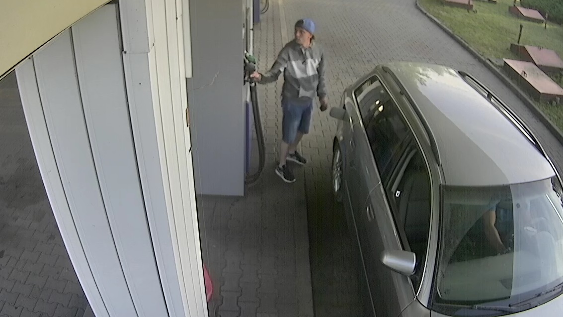 Obraz z monitoringu sprawców kradzieży paliwa.Przedstawia mężczyznę obok samochodu. 