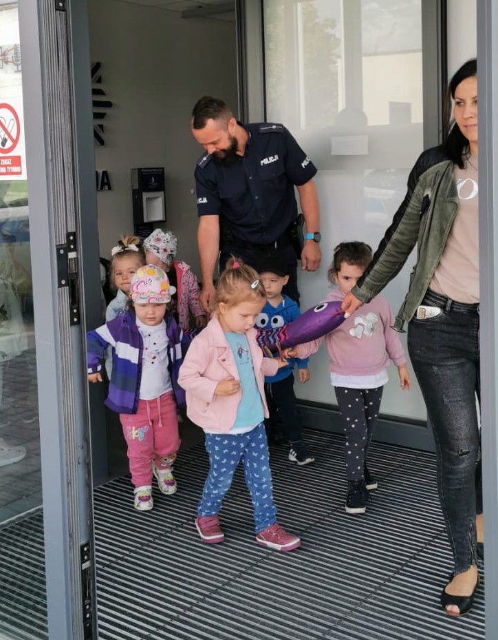 Policjant wyprowada grupę dzieci z wojkowickiego komisariatu