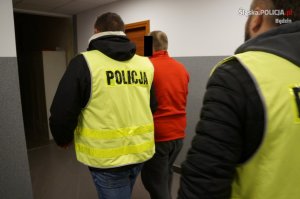 Policjanci doprowadzają zatrzymanego mężczyznę