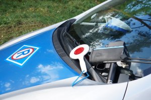 Maska policyjnego radiowozu na której leży urządzenie do pomiaru prędkości oraz tarcza sygnalizacyjna