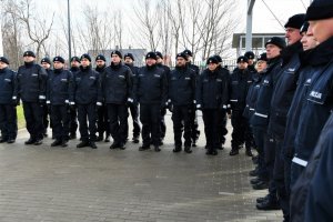 Grupa policjantów biorących udział w uroczystości stoi w szeregu.