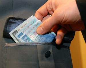 Dłoń wkładająca plik banknotów do kieszeni