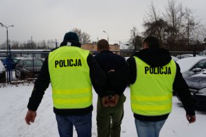 Dwaj nieumundurowani policjanci prowadzą mężczyznę