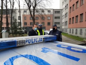 Dach radiowozu w tle Komandant Powiatowy Policji w Będzinie  wraz ze Starostą Powiatu Będzińskiego