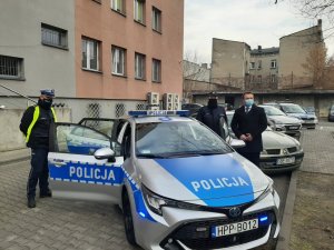 Komandant Powiatowy Policji w Będzinie oraz policjant ruchu drogowego wraz ze Starostą Powiatu Będzińskiego stojący obok radiowozu