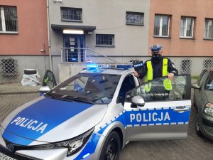 Policjant ruchu drogowego stojący obok radiowozu