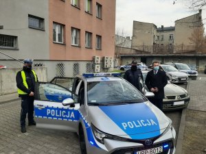 Komandant Powiatowy Policji w Będzinie oraz policjant ruchu drogowego wraz ze Starostą Powiatu Będzińskiego stojący obok radiowozu