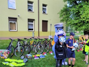 Dzieci stojące przed rowerami z gadżetami policyjnymi oraz policyjna maskotka &quot;Klara&quot;