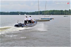 Policjanci płynący motorówką na zbiorniku wodnym.