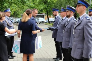 Na fotografii widoczny Starosta Będziński który wręcza nagrody wyróżnionym policjantom. Nagrody podaje mu kobieta.