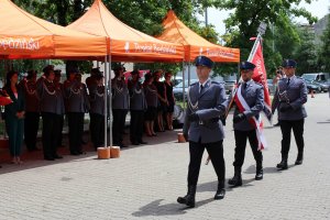 Odprowadzany Sztandar Komendy Powiatowej Policji w Będzinie, w tle goście i salutujący policjanci.