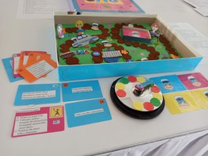 Na zdjęciu widoczna gra planszowa z konkursu edukacyjnego, plansza do gry oraz pytania do gry.