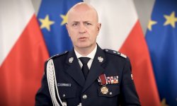 Komendant Główny Policji w mundurze galowym na tle flag Polski i Unii Europejskiej.