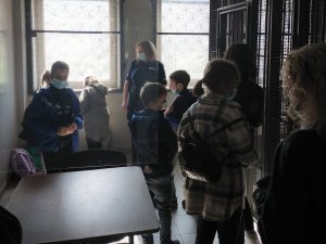 Policjantka pokazuje dzieciom pomieszczenie, gdzie przebywają osoby zatrzymane przez policjantów.