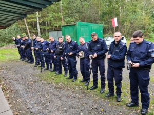 Policjanci stojący w rzędzie podczas sprawdzenia broni na strzelnicy