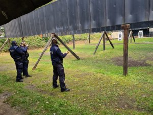 Policjanci pokazujący instruktorowi do sprawdzenia broń służbową po zakończonym strzelaniu na strzelnicy.