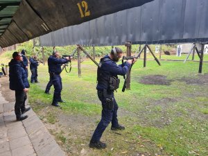 Policjanci oddający strzały na strzelnicy z pistoletu maszynowego.