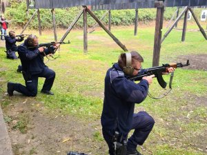 Policjanci w pozycji klęczącej oddający strzały z karabinu maszynowego podczas wyszkolenia strzeleckiego