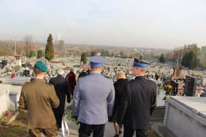 Grupa ludzi idąca cmentarną drogą. Na pierwszym planie przedstawiciele służb mundurowych, od lewej: Wojska, Policji i Straży Pożarnej.