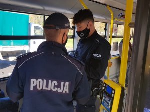 Dwóch policjantów prowadzących kontrolę w autobusie.