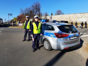 Policjanci stojący przy radiowozie podczas działań &quot;ZNICZ 2021&quot;