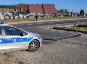 Radiowóz policyjny stojący przy cmentarzu.