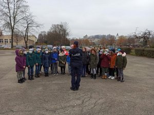 Umundurowana policjantka stojąca przed grupą młodzieży i przemawiająca do nich