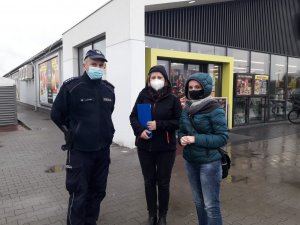 Policjant oraz pracownice sanepidu przed jednym z marketów, który poddano kontroli