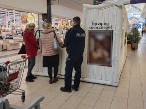 Policjant wraz z pracownicami sanepidu w trakcie kontroli punktu sprzedażowego na pasażu galerii handlowej