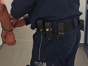 Policjant zakładający kajdanki zatrzymanemu mężczyźnie