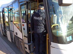 Dwóch umundurowanych policjantów wchodzących do autobusu.