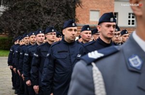 Zdjęcie kolorowe. Widoczni umundurowani policjanci na placu podczas ślubowania