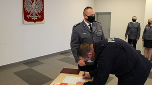 Policjant składający podpis pod aktem ślubowania w obecności Komendanta Powiatowego Policji w Będzinie.
