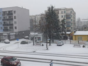 Na zdjęciu widoczna droga pokryta śniegiem oraz zaśnieżone samochody.