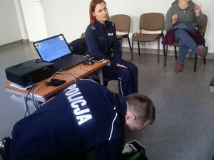 Policjantka i policjant siedzący przy stanowisku, gdzie wyświetlana jest prezentacja multimedialna