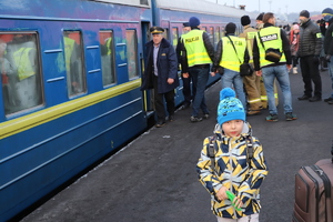 Na pierwszym planie mały chłopczyk, za nim znajdują się policjanci, którzy pomagają wysiadać ludziom z pociągu.