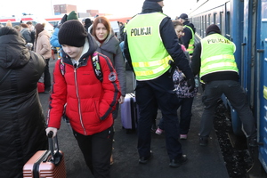 Na pierwszym planie widzimy kobietę z dzieckiem, na drugim planie widoczni policjanci, którzy pomagają przy wyjściu z pociągu.