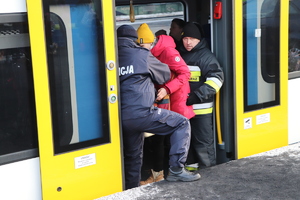 Policjant i strażak pomagający ludziom wsiadać do pociągu.