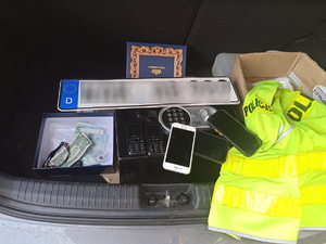 Zatrzymane przez policjantów rzeczy, które są w bagażniku samochodu : telefony, pieniądze, sejf, tablice rejestracyjne.