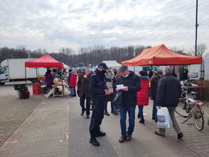 Policjant rozmawiający z mężczyzną na targowisku miejskim w Będzinie.