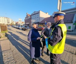 Policjant dający odblaski dwóm kobietom.