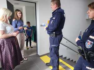 Policjant oraz policjantka, którzy stoją w towarzystwie kobiety rozmawiają z kobietą, która otworzyła drzwi mieszkania. Na drugim planie widoczny mały chłopiec.