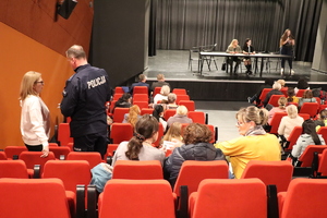 Policjant rozmawiający z kobietą na sali przed sceną.