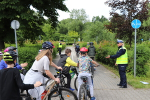 Policjanci nadzorujący jazdę dzieci na rowerach.