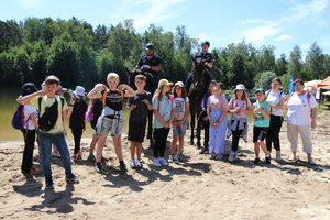 Na zdjęciu widać grupę dzieci stojących obok patrolu konnego Policji
