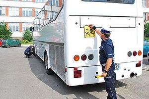 Policjant sprawdzający stan techniczny autokaru.