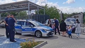 Policjanci prezentują grupie dzieci radiowóz przed wojkowickim komisariatem